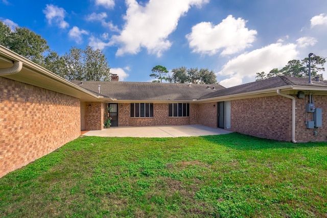 back of property with a lawn and a patio