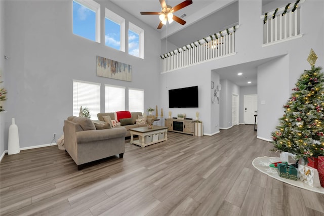 living room featuring a high ceiling, light hardwood / wood-style flooring, a wealth of natural light, and ceiling fan