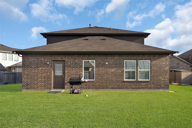 back of property featuring a yard, fence, and brick siding