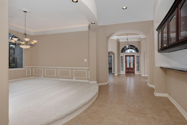 foyer with crown molding, baseboards, light tile patterned floors, an inviting chandelier, and arched walkways