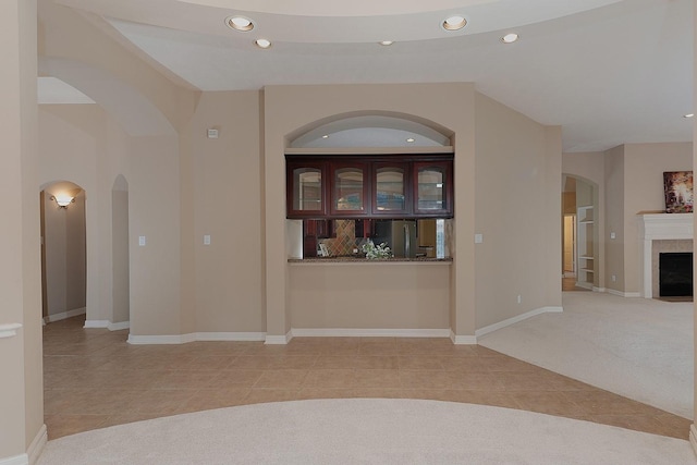 hall with light tile patterned floors, baseboards, arched walkways, and recessed lighting