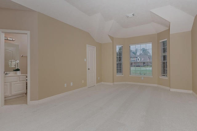 empty room with vaulted ceiling, baseboards, visible vents, and light carpet