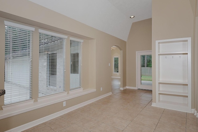 interior space with arched walkways, a wealth of natural light, baseboards, and vaulted ceiling