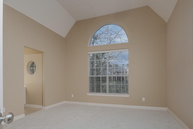 unfurnished room featuring baseboards, carpet floors, and high vaulted ceiling