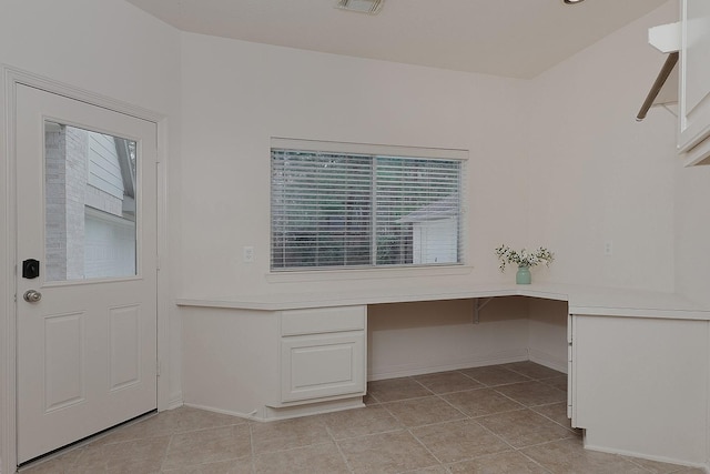 unfurnished office featuring light tile patterned floors, visible vents, built in study area, and baseboards