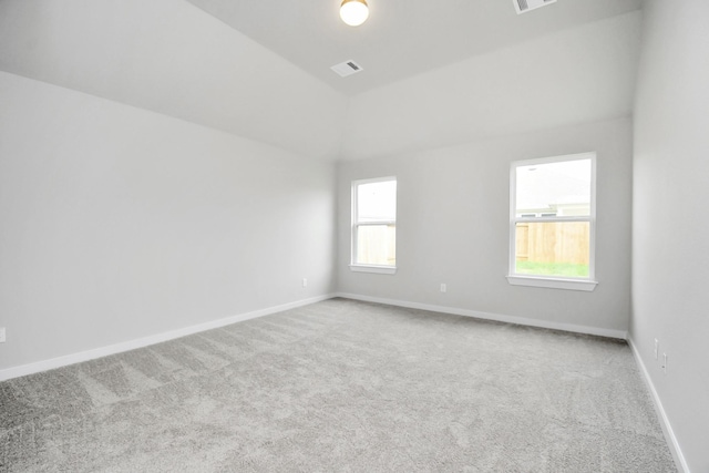 carpeted empty room with vaulted ceiling