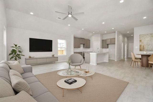 living room featuring light hardwood / wood-style floors, ceiling fan, lofted ceiling, and sink