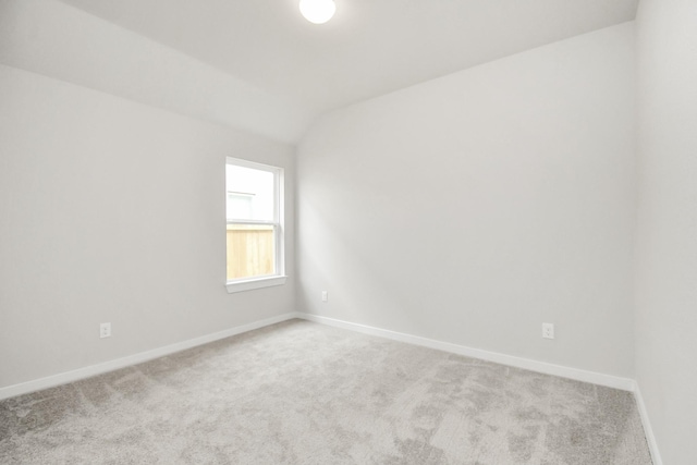 unfurnished room with light carpet and vaulted ceiling