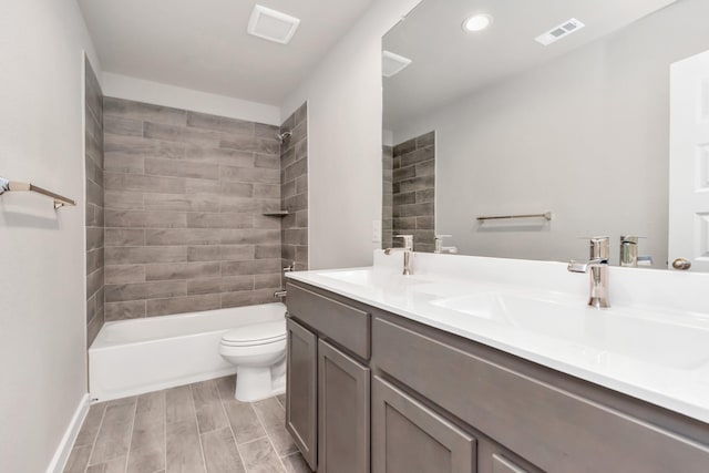 full bathroom featuring vanity, tiled shower / bath combo, and toilet