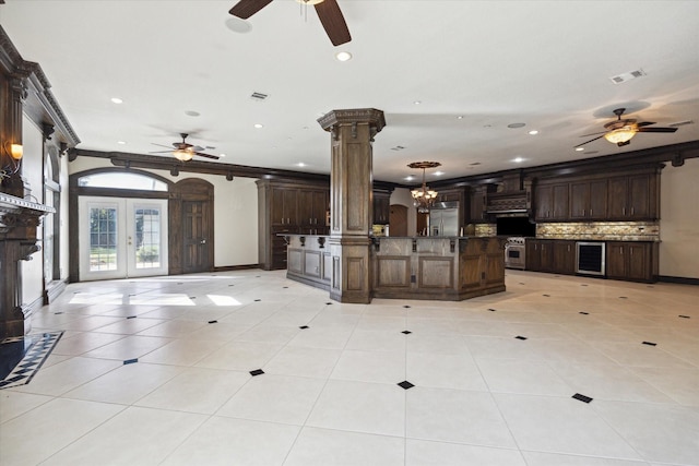 interior space with ornate columns, crown molding, french doors, and dark brown cabinets