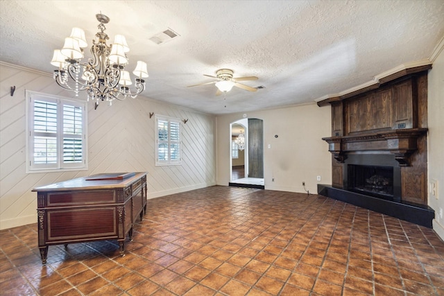 living room featuring ornamental molding, ceiling fan with notable chandelier, a large fireplace, and a healthy amount of sunlight