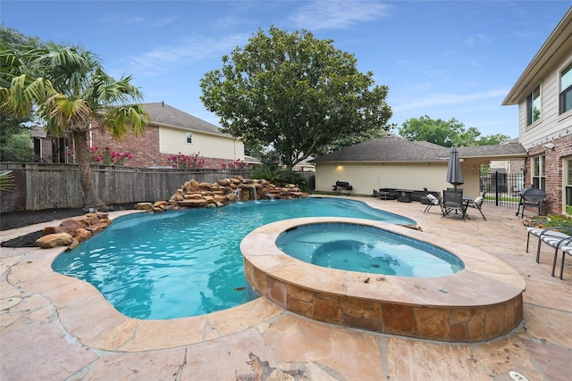 view of swimming pool featuring an in ground hot tub, pool water feature, a patio, and grilling area