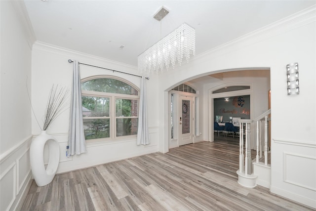 interior space featuring a notable chandelier, wood-type flooring, and ornamental molding