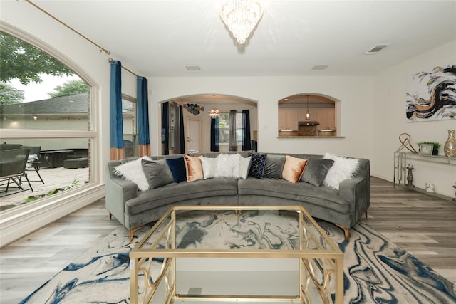 living room with hardwood / wood-style flooring, a healthy amount of sunlight, and an inviting chandelier