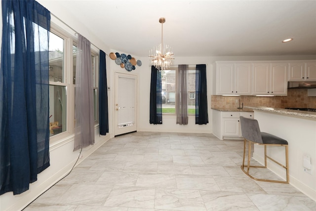 kitchen featuring white cabinets, decorative backsplash, and hanging light fixtures