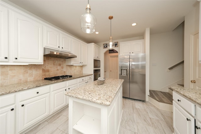 kitchen featuring appliances with stainless steel finishes, a center island, light stone counters, and pendant lighting