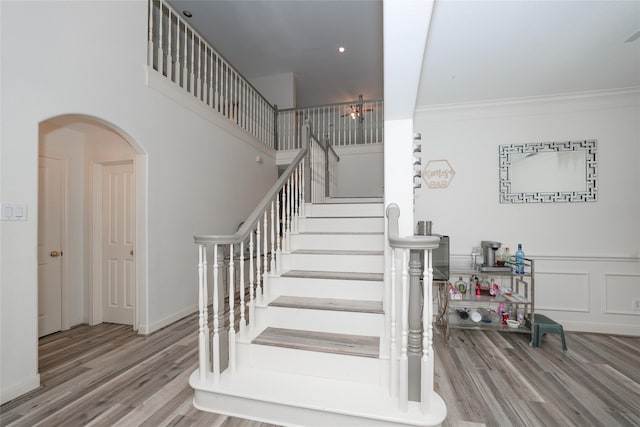 stairs with wood-type flooring and ornamental molding