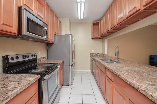 kitchen with light stone countertops, sink, stainless steel appliances, a textured ceiling, and light tile patterned floors