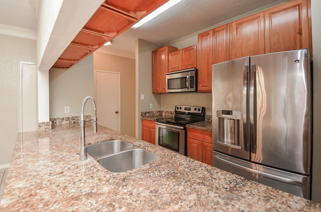 kitchen with sink, ornamental molding, light stone counters, kitchen peninsula, and stainless steel appliances