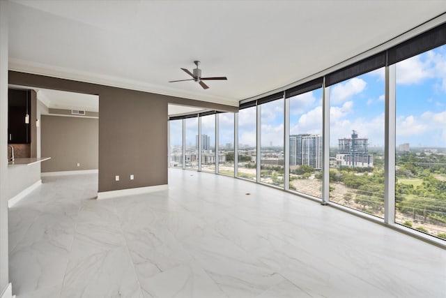 empty room with floor to ceiling windows, a wealth of natural light, ornamental molding, and ceiling fan