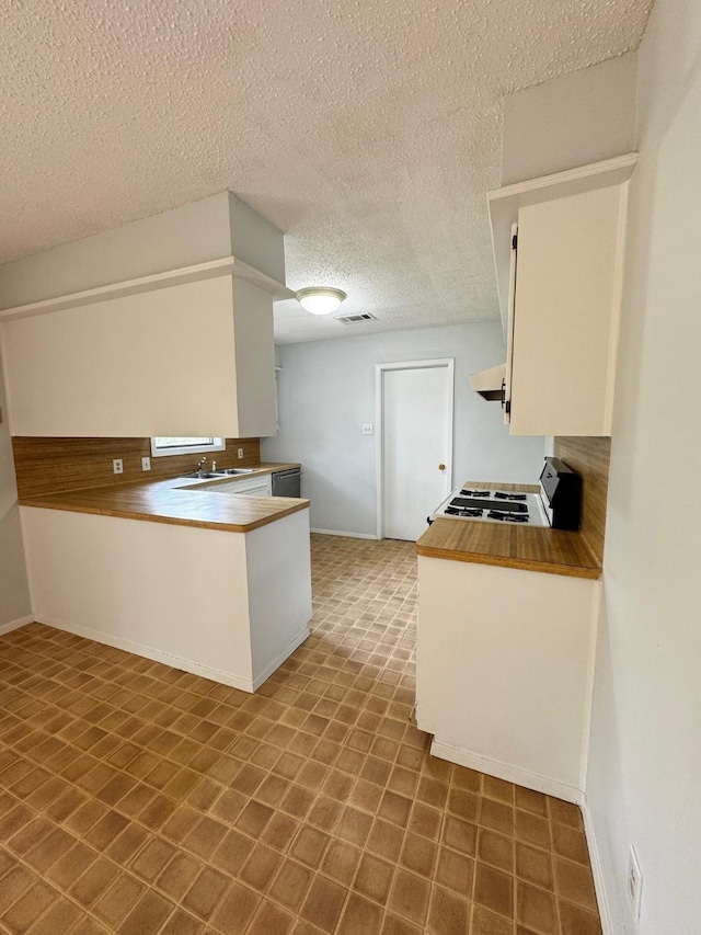 kitchen with white range oven, kitchen peninsula, a textured ceiling, white cabinets, and exhaust hood