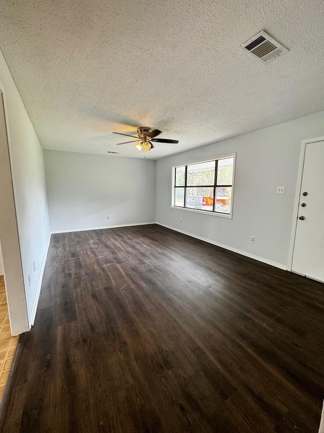 empty room featuring dark hardwood / wood-style floors, ceiling fan, and a textured ceiling