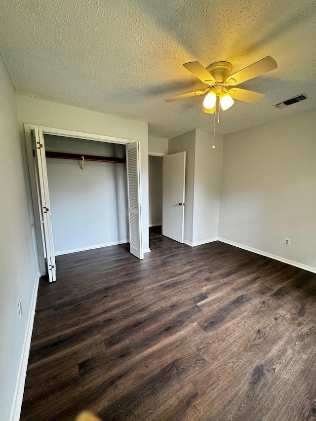 unfurnished bedroom featuring a textured ceiling, ceiling fan, dark wood-type flooring, and a closet