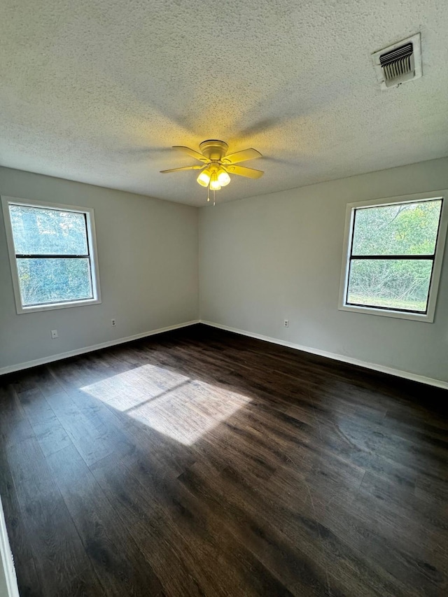 spare room with plenty of natural light, dark hardwood / wood-style flooring, and a textured ceiling