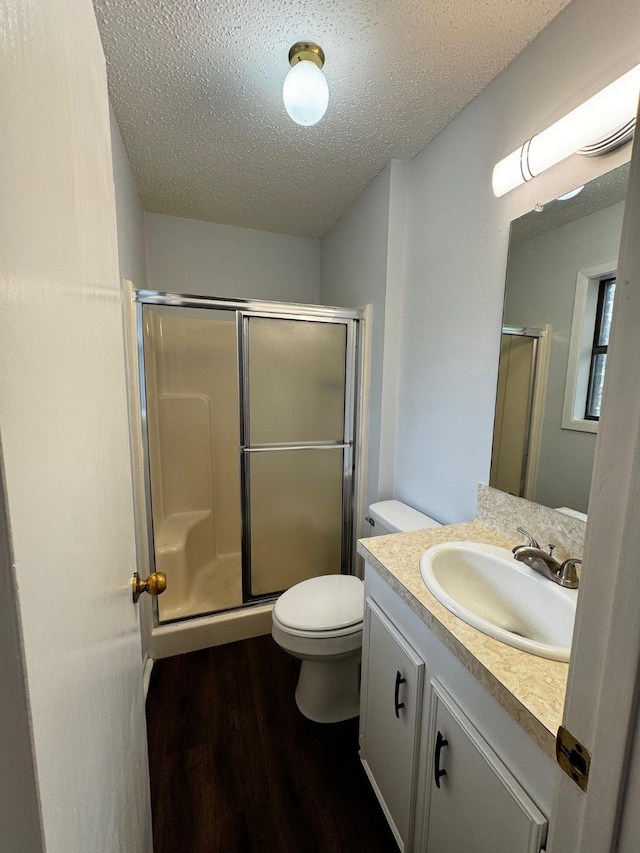 bathroom with hardwood / wood-style floors, toilet, a textured ceiling, and walk in shower