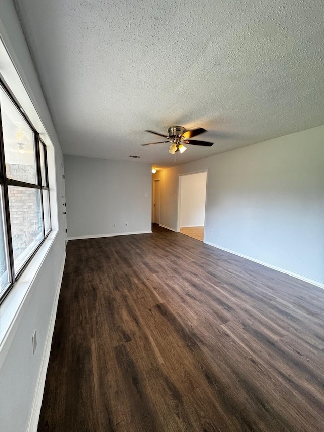 empty room featuring a textured ceiling, ceiling fan, and dark hardwood / wood-style floors