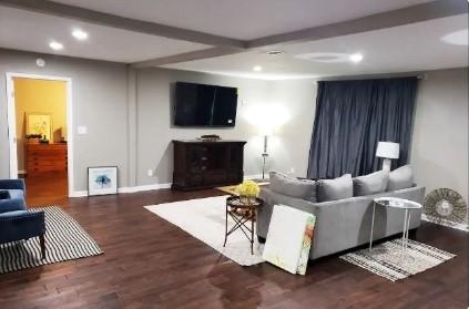 living room featuring beamed ceiling and dark hardwood / wood-style flooring