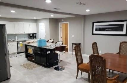 kitchen featuring a center island, light colored carpet, a breakfast bar area, white cabinets, and appliances with stainless steel finishes