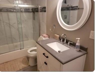 full bathroom with vanity, toilet, and bath / shower combo with glass door