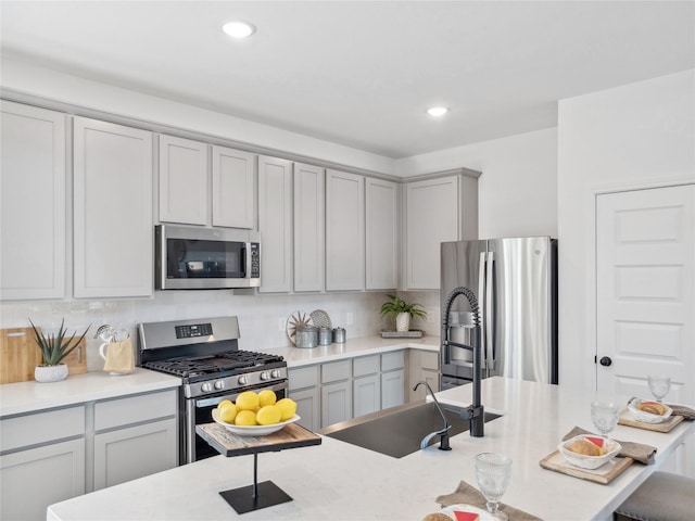 kitchen featuring stainless steel appliances, tasteful backsplash, gray cabinetry, and sink