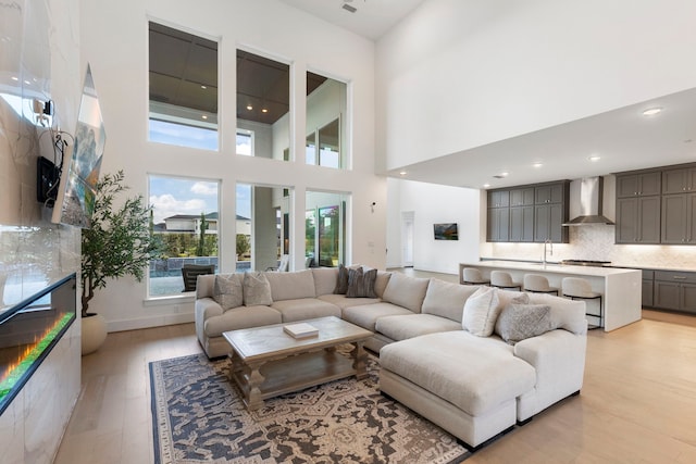 living room with light hardwood / wood-style floors, sink, and a high ceiling