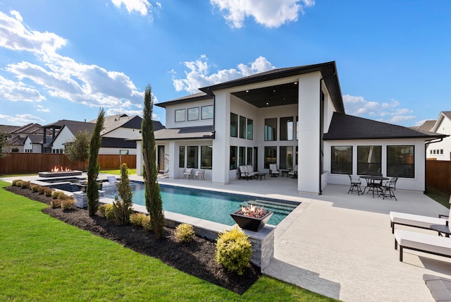 rear view of house with a fenced in pool, a patio area, and a lawn