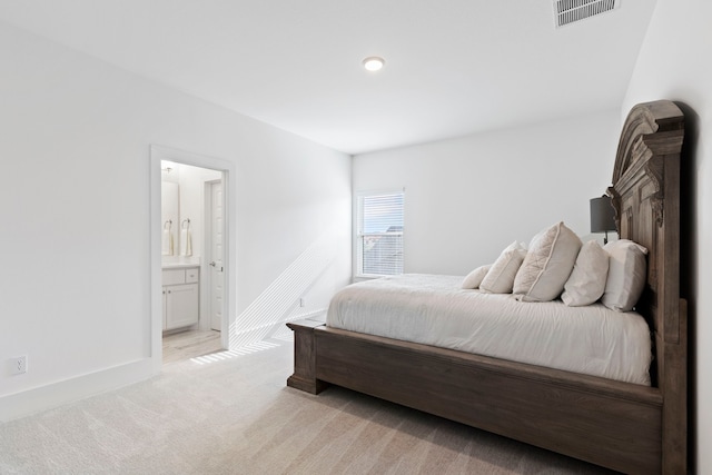 bedroom with ensuite bath and light carpet