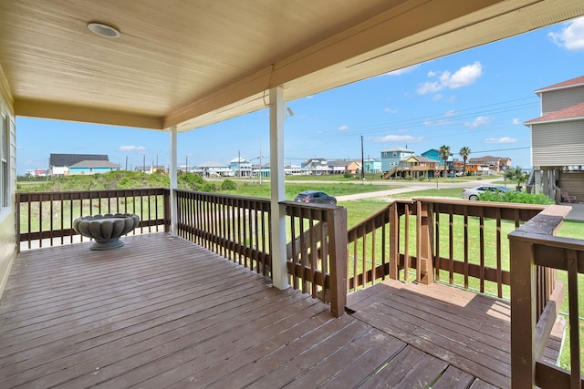 wooden terrace with a lawn and covered porch