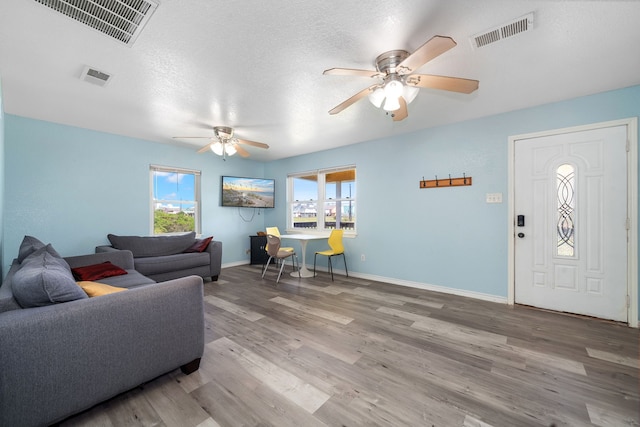 living room featuring hardwood / wood-style flooring, ceiling fan, and a textured ceiling