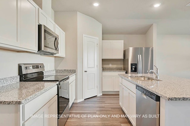 kitchen with hardwood / wood-style floors, a kitchen island with sink, white cabinets, sink, and appliances with stainless steel finishes