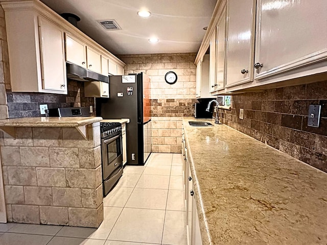 kitchen featuring gas stove, light tile patterned floors, and sink