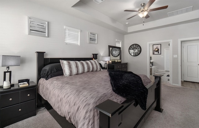 carpeted bedroom with connected bathroom, a raised ceiling, and ceiling fan