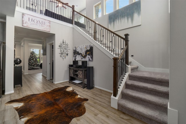 stairway with a high ceiling, hardwood / wood-style flooring, and a wealth of natural light