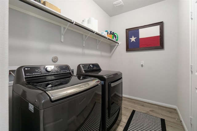 laundry area with washing machine and dryer and light hardwood / wood-style flooring