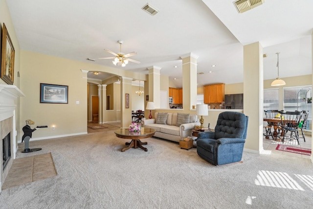 living room with a fireplace, light carpet, and ceiling fan