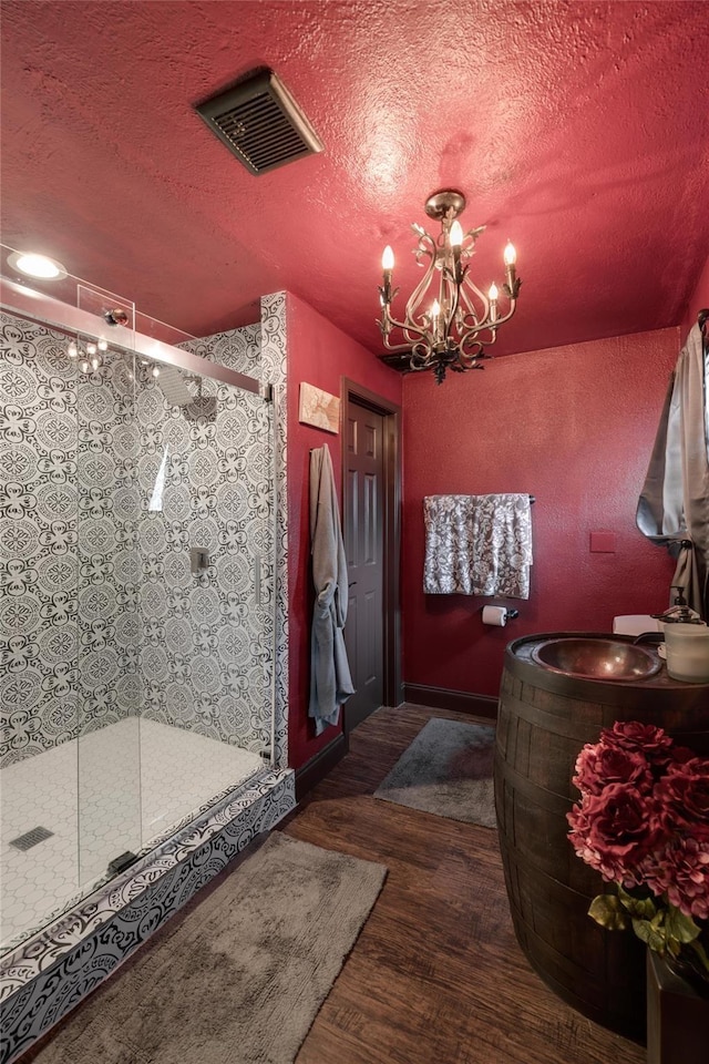 bathroom with walk in shower, an inviting chandelier, a textured ceiling, and hardwood / wood-style flooring