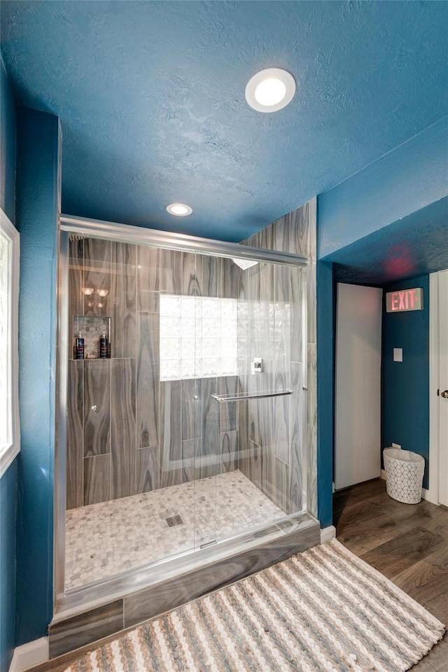 bathroom featuring tiled shower, wood-type flooring, and a textured ceiling