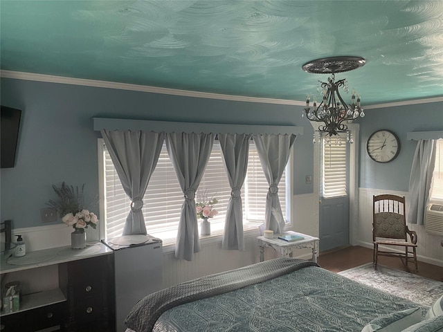 bedroom with hardwood / wood-style floors, ornamental molding, and a chandelier