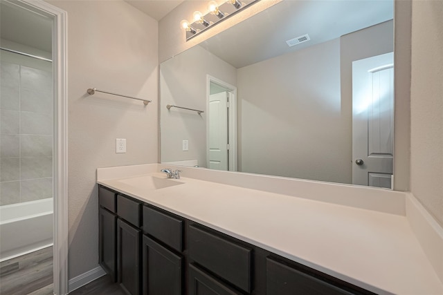 bathroom with shower / bathing tub combination, hardwood / wood-style floors, and vanity