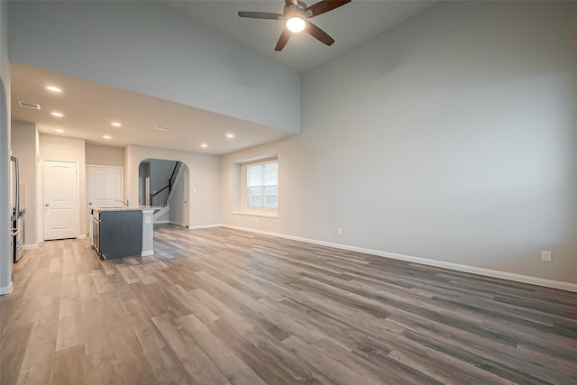 unfurnished living room featuring ceiling fan, dark hardwood / wood-style flooring, high vaulted ceiling, and sink